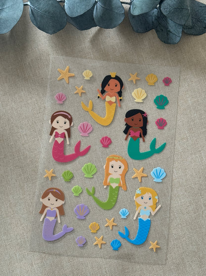 Rub On Aufkleber Meerjungfrauen A5 Warum du unsere Rub-Ons lieben wirst:  ✔ Randloser Premium-Look   ✔ Besondere Haptik   ✔ Präzise Platzierung dank transparenter Trägerfolie  ✔ Wasser- und kratzfest // Hitze- und UV-beständig   ✔ Starke Haftung auf Glas, Keramik, Holz, Raysin u.v.m.  ✔ Langlebig und hochwertig verarbeitet  ✔ Auch gewerblich nutzbar – keine zusätzliche Lizenz nötig